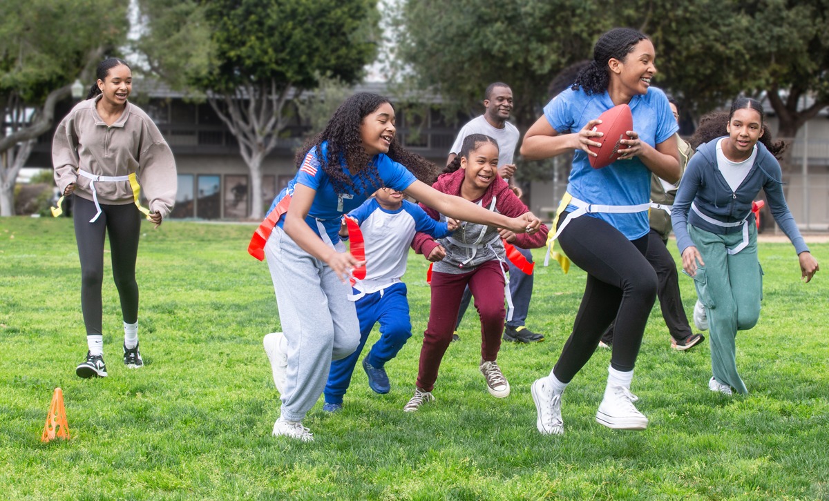 A family plays flag football in their front yard.