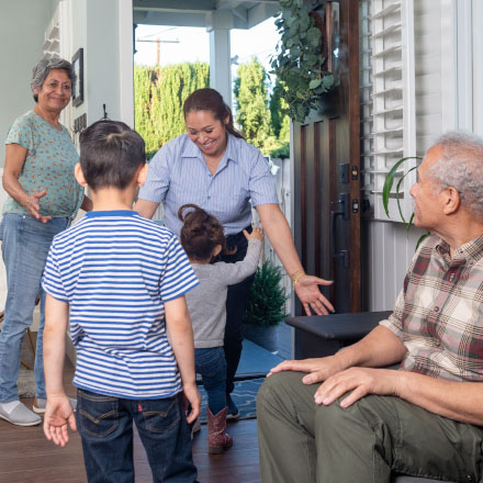 A mother being greeted by her children at the door